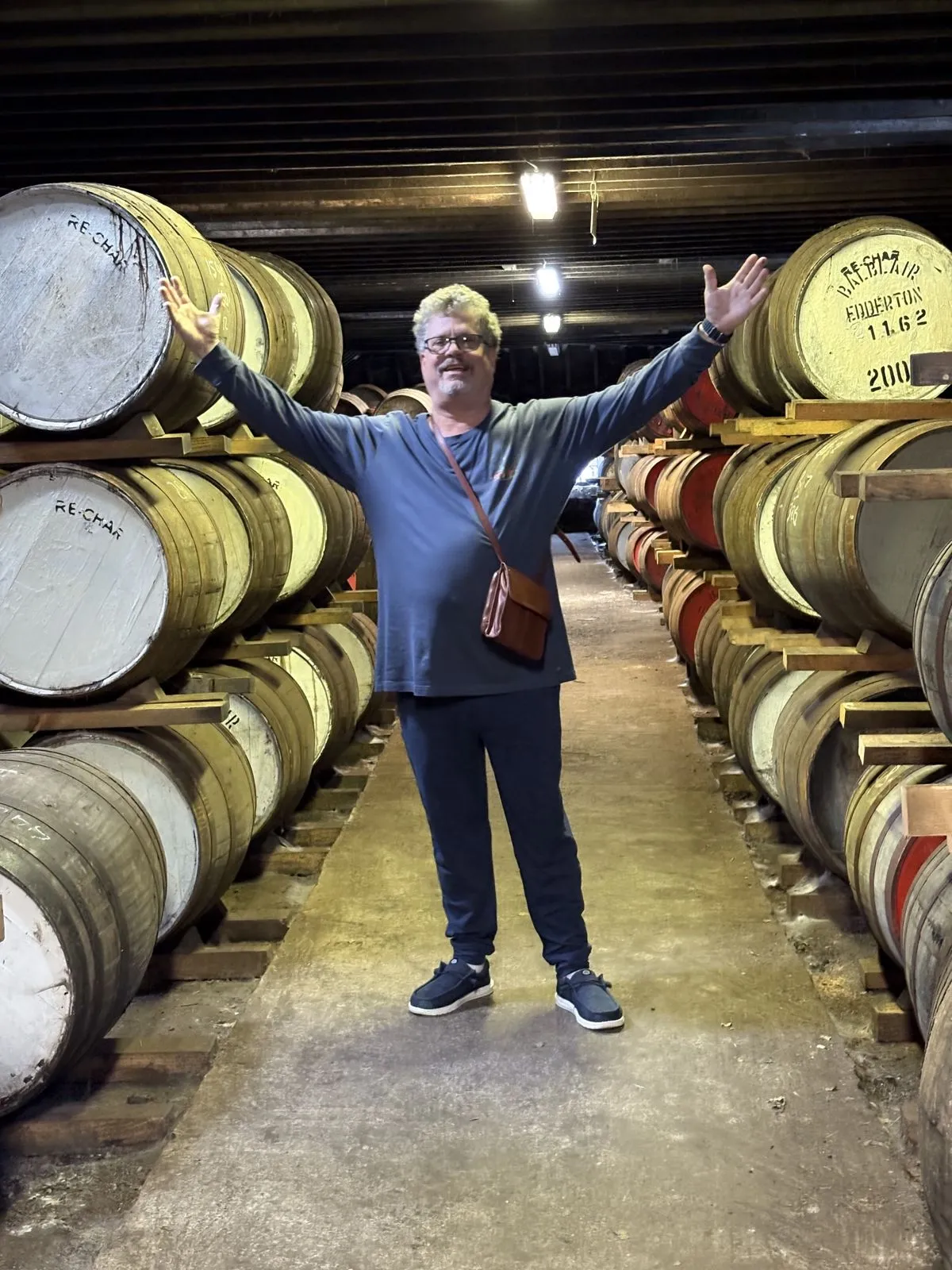 David with arms spread wide in a barrel-aging room.